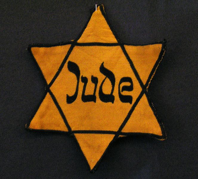 Yellow badge Star of David called "Judenstern". Part of the exhibition in the Jewish Museum Westphalia, Dorsten, Germany. The wording is the German word for Jew (Jude), written in mock-Hebrew script. (Source: Wikipedia)