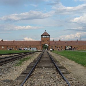 The gatehouse at the former German Nazi concentration camp of Auschwitz II (Birkenau), leading to the gas chambers. Note that this is inside the camp looking back from the loading ramp to the "Gate of Death". The gatehouse was built in 1943 and the rail spur began operating in May 1944. Before then, deportees arrived at the old Judenrampe over two kilometres away and either walked or were taken in trucks to the gas chambers. (Source:Wikipedia)